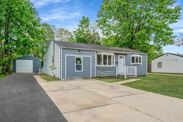 view of front facade featuring an outdoor structure, a garage, aphalt driveway, and a front yard