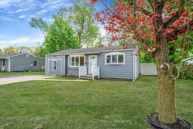 view of front of property featuring fence, driveway, and a front lawn