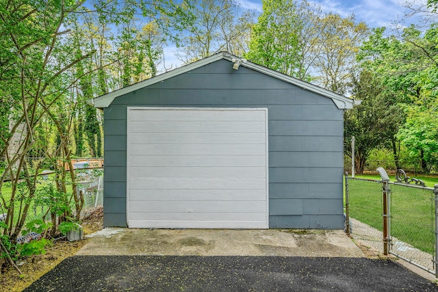 detached garage with fence, a gate, and driveway