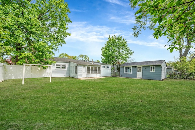 rear view of house with a fenced backyard, an outbuilding, and a lawn