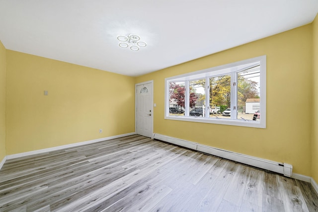 unfurnished room with baseboards, baseboard heating, and wood finished floors