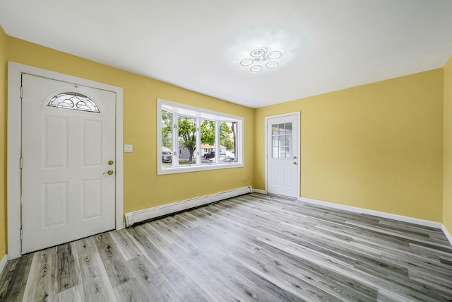 foyer entrance featuring baseboards, a baseboard heating unit, and wood finished floors