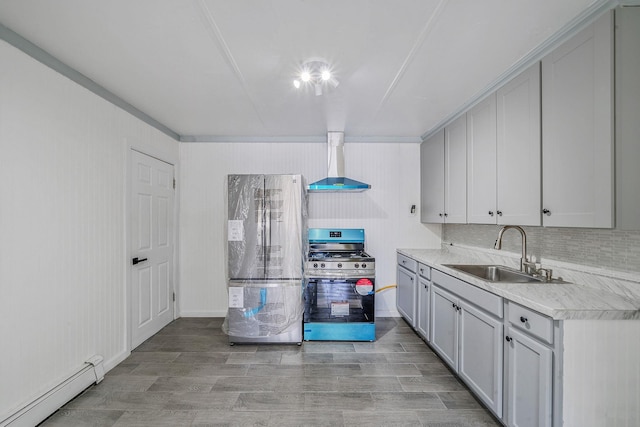 kitchen with a sink, baseboard heating, light countertops, freestanding refrigerator, and gas range