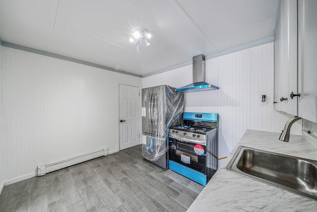 kitchen featuring baseboard heating, a sink, gas stove, wall chimney exhaust hood, and wood finished floors