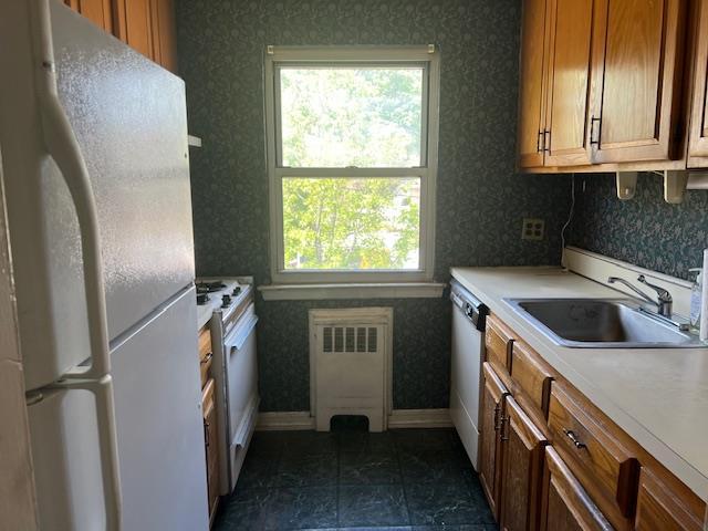 kitchen featuring white appliances, plenty of natural light, a sink, and radiator