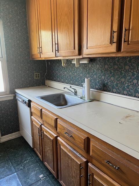kitchen featuring white dishwasher, light countertops, wallpapered walls, and a sink