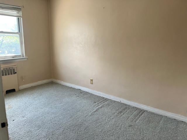 carpeted empty room with baseboards and radiator