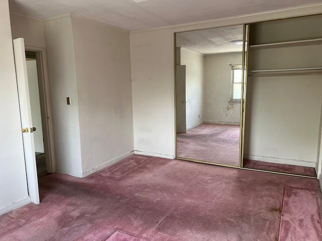 unfurnished bedroom with carpet flooring, baseboards, and a closet