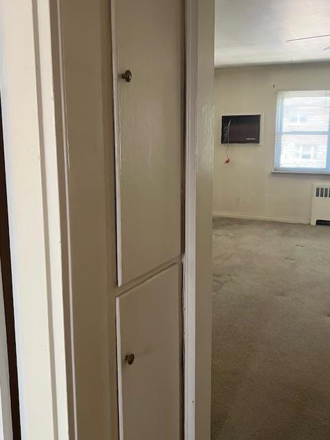 hallway featuring baseboards, carpet, and radiator heating unit