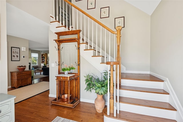stairway featuring baseboards, vaulted ceiling, and wood finished floors