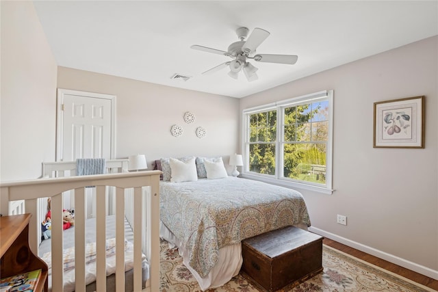 bedroom with baseboards, ceiling fan, wood finished floors, and visible vents
