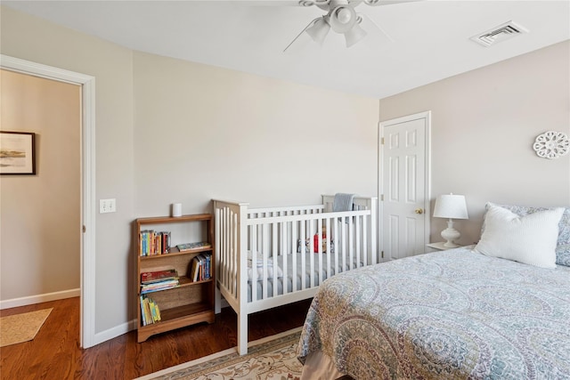 bedroom with baseboards, ceiling fan, wood finished floors, and visible vents
