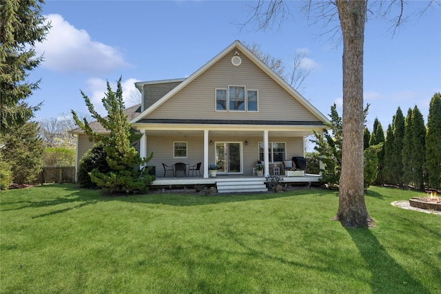 rear view of house with a lawn, fence, and a porch