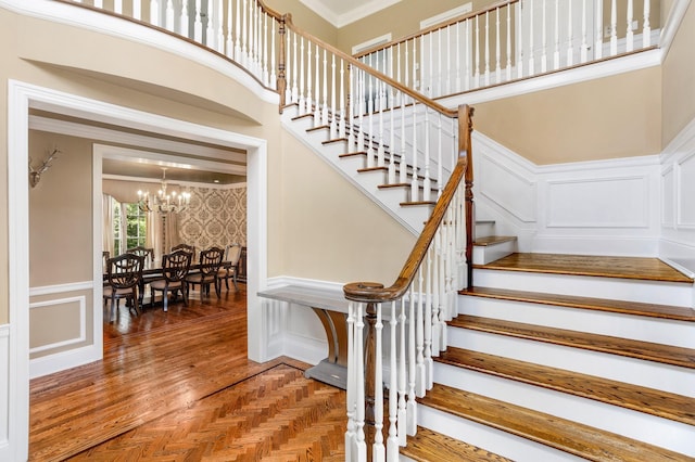 9 Earle Dr, Muttontown, NY 11791 - staircase with a decorative wall, a chandelier, crown molding, wainscoting, and a high ceiling