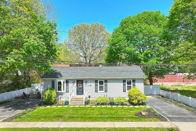 ranch-style home with roof with shingles and a front yard
