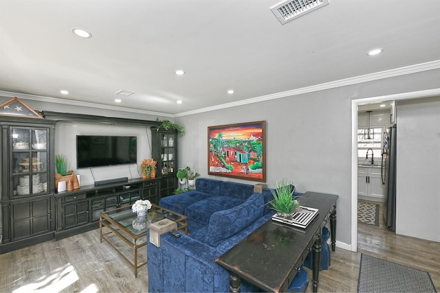 living room with crown molding, recessed lighting, wood finished floors, and visible vents