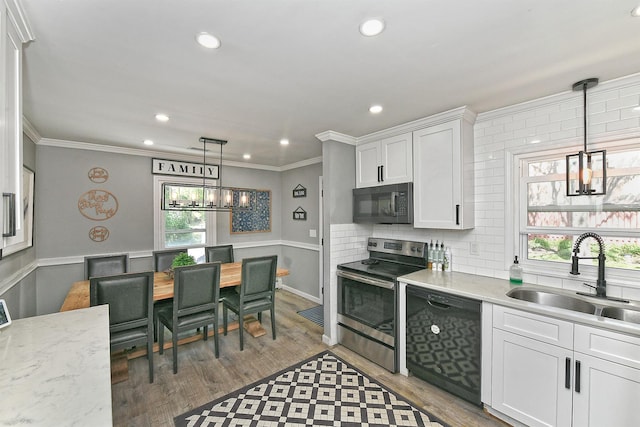 kitchen with crown molding, wood finished floors, white cabinets, a sink, and black appliances