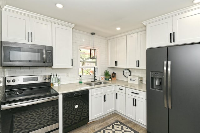 kitchen featuring appliances with stainless steel finishes, wood finished floors, a sink, light countertops, and white cabinets