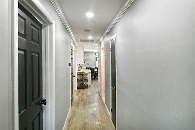 corridor with crown molding, visible vents, light wood-style floors, baseboards, and recessed lighting