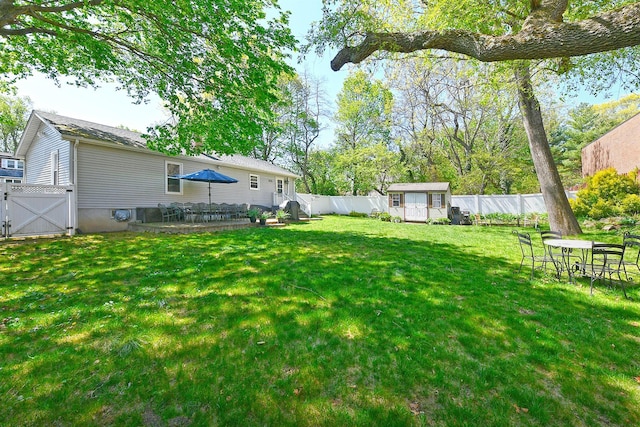 view of yard featuring an outdoor structure, a gate, a fenced backyard, and a shed