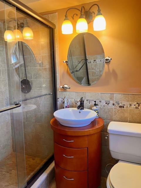 bathroom featuring tile walls, a shower stall, and a wainscoted wall