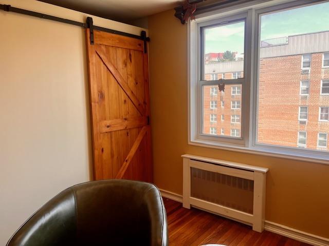 sitting room with baseboards, dark wood finished floors, and a barn door