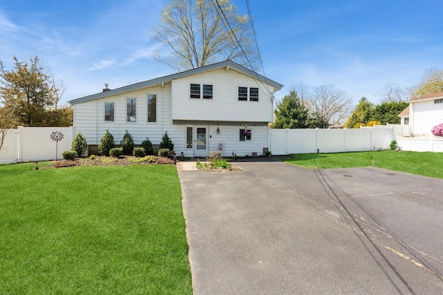 split level home with fence and a front lawn