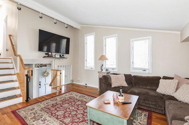 living area featuring stairs, rail lighting, vaulted ceiling, and wood finished floors