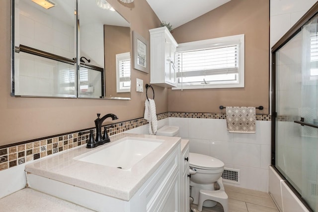 full bath featuring vanity, toilet, tile walls, lofted ceiling, and visible vents