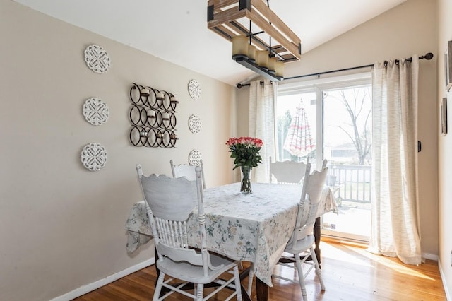 dining room featuring baseboards, vaulted ceiling, and wood finished floors