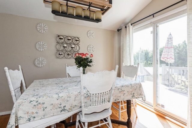 dining space with wood finished floors and lofted ceiling