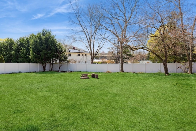 view of yard featuring a fenced backyard and a fire pit