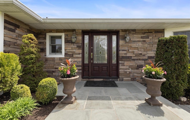 entrance to property with a porch and stone siding