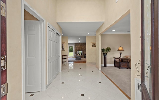corridor with light colored carpet, recessed lighting, baseboards, light tile patterned floors, and a towering ceiling