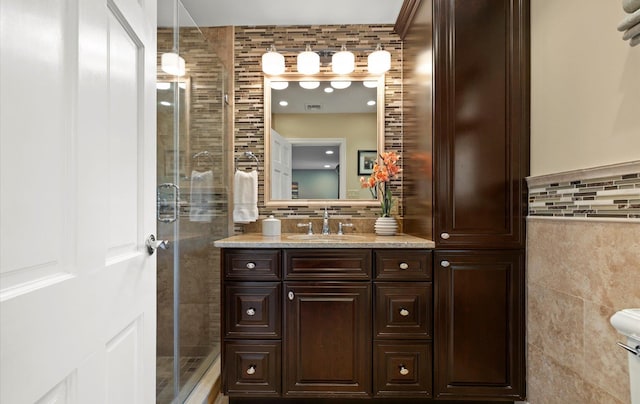 full bathroom featuring decorative backsplash, tile walls, a shower stall, and vanity