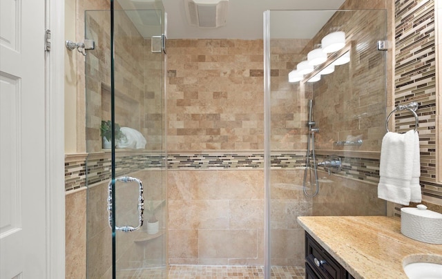 full bath featuring vanity, a stall shower, and tile walls