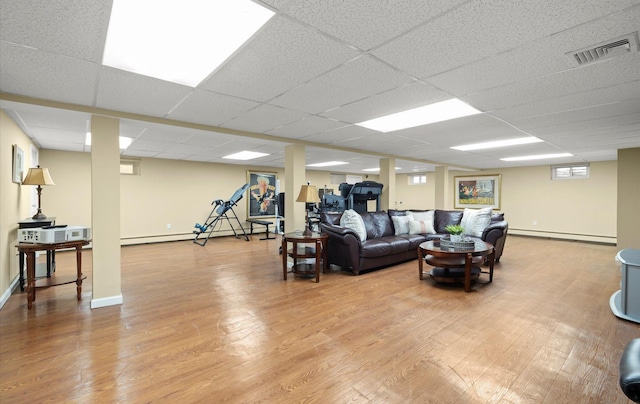 living room featuring visible vents, baseboards, a drop ceiling, wood finished floors, and a baseboard heating unit