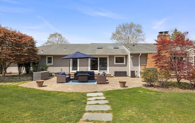rear view of house with outdoor lounge area, roof with shingles, a chimney, a patio area, and a lawn