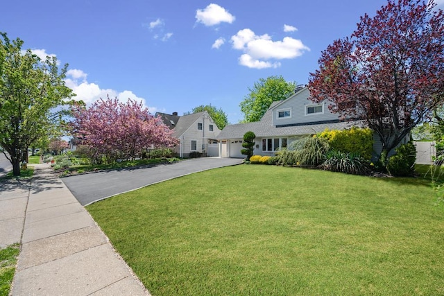 view of front of property with an attached garage, a front yard, and aphalt driveway