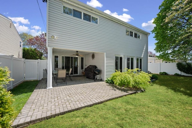 rear view of house featuring a lawn, ceiling fan, a fenced backyard, and a patio area