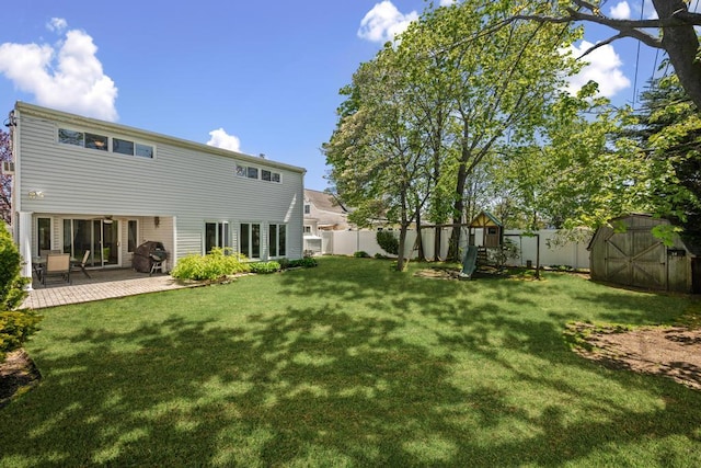 rear view of property featuring a storage shed, an outbuilding, a lawn, and a fenced backyard