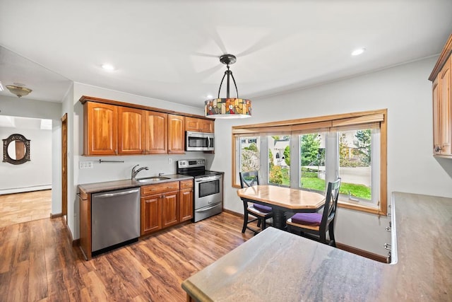 kitchen with stainless steel appliances, baseboards, a sink, and wood finished floors