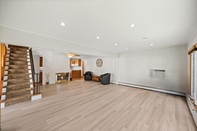 interior space with ceiling fan, a wall mounted air conditioner, a fireplace, light wood-style flooring, and stairway