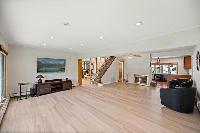living area with a baseboard radiator, light wood-type flooring, visible vents, and stairs