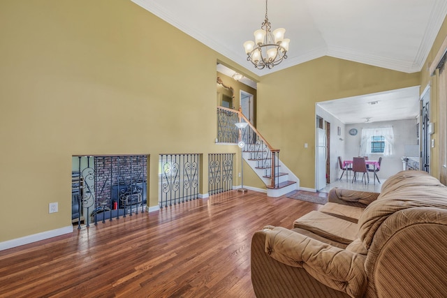 living area featuring ornamental molding, stairs, wood finished floors, a notable chandelier, and vaulted ceiling