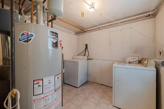clothes washing area with washing machine and clothes dryer, laundry area, light tile patterned floors, and water heater