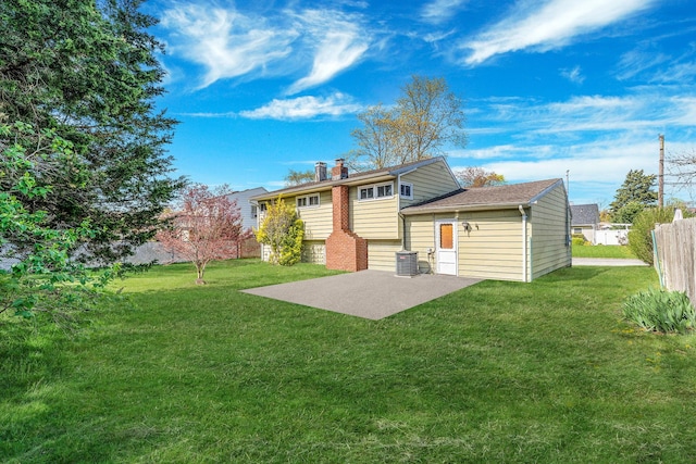 rear view of house with fence, a chimney, a patio area, central air condition unit, and a lawn
