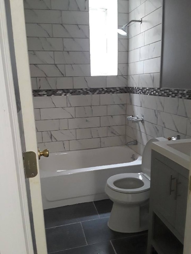 bathroom with tile walls, shower / tub combination, vanity, tile patterned floors, and toilet