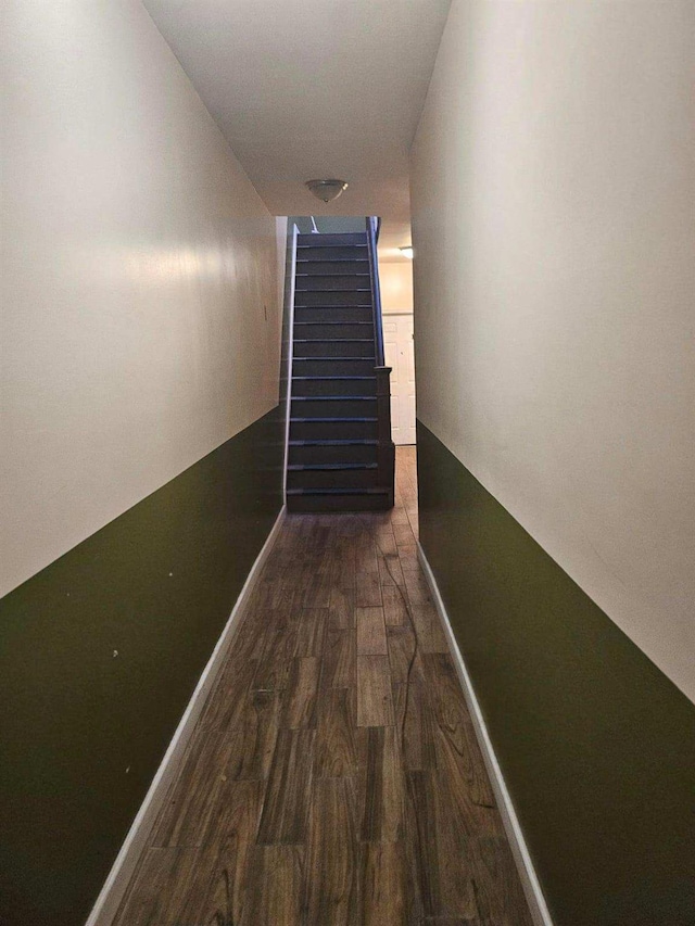 corridor featuring stairs, baseboards, and wood finished floors