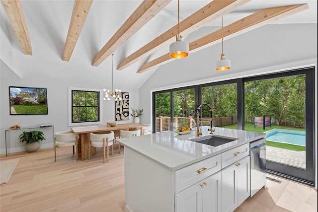 kitchen with light countertops, a wealth of natural light, lofted ceiling with beams, and a sink